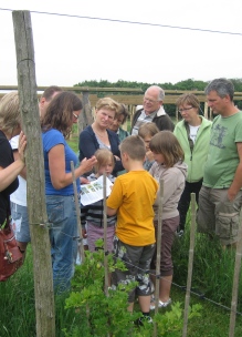 Een groep met diverse leeftijden krijgt uitleg in de biologische tuin van Sprankenhof met speurtocht voor de kinderen