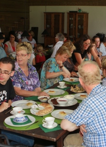 Groep mensen geniet aan tafel van theeleut hightea met diverse huisgemaakte zoete en hartige lekkernijen bij Sprankenhof Udenhout Tilburg
