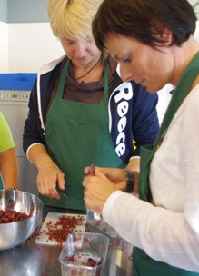 Twee dames maken fruit schoot tijdens biologische workshop fruitbereiding in kookstudio Sprankenhof in Udenhout